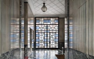 Piazza VI Febbraio 10, progetto di Renato Ferrari, 1934-36. Pavimento in palladiana di marmo e calcare dal bianco al grigio e al nero, disposti secondo un motivo degradé; basamento in calcare Grigio Carnico; pareti in marmo Cipollino 900, noto come marmo Zebrino. Foto ©Paola Pansini.